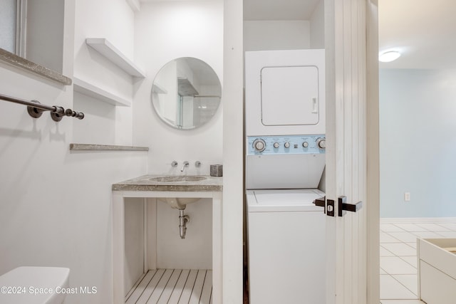 bathroom featuring stacked washer / drying machine, tile patterned floors, and sink