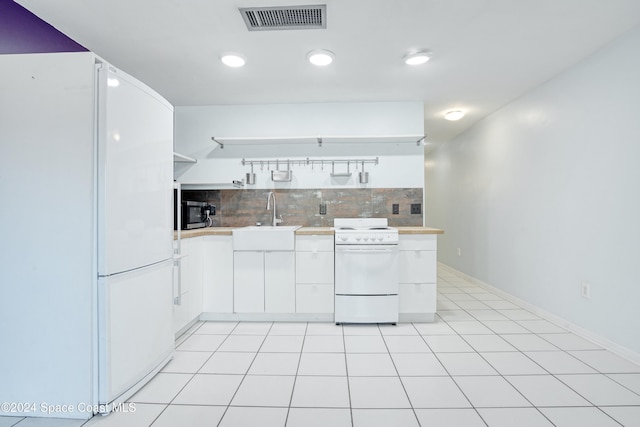 kitchen with sink, light tile patterned floors, white cabinets, white appliances, and backsplash