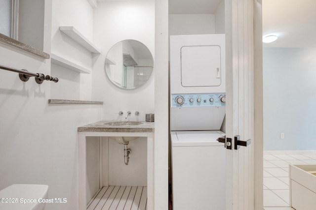 bathroom featuring stacked washer and dryer, sink, and tile patterned floors