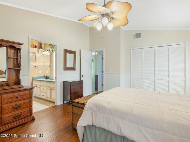 bedroom with lofted ceiling, ensuite bathroom, light hardwood / wood-style flooring, ceiling fan, and a closet