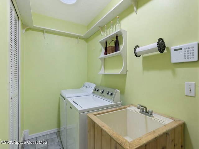 clothes washing area with washing machine and clothes dryer, sink, and light tile patterned floors