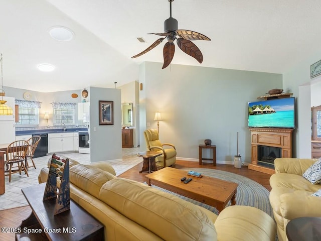 living room with ceiling fan, sink, and vaulted ceiling