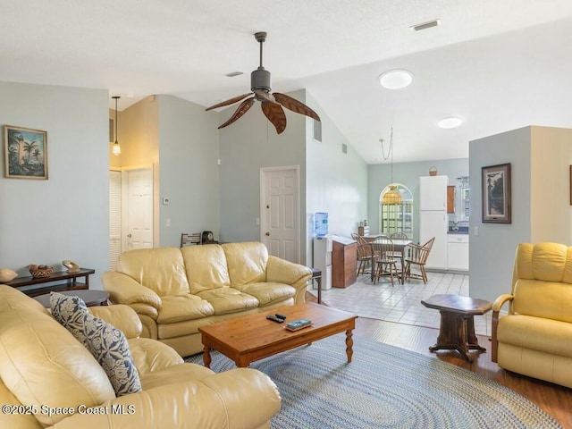 living room featuring ceiling fan, light hardwood / wood-style floors, and vaulted ceiling