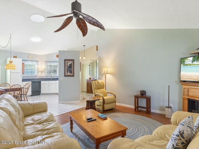 living room with ceiling fan, lofted ceiling, sink, and light hardwood / wood-style flooring