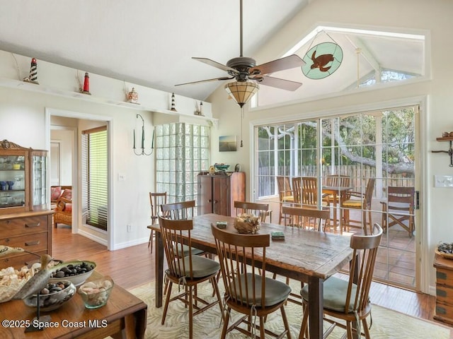 dining room with ceiling fan, light wood-type flooring, a wealth of natural light, and vaulted ceiling