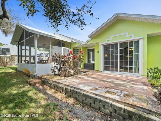 back of house with a lawn, a sunroom, and a patio