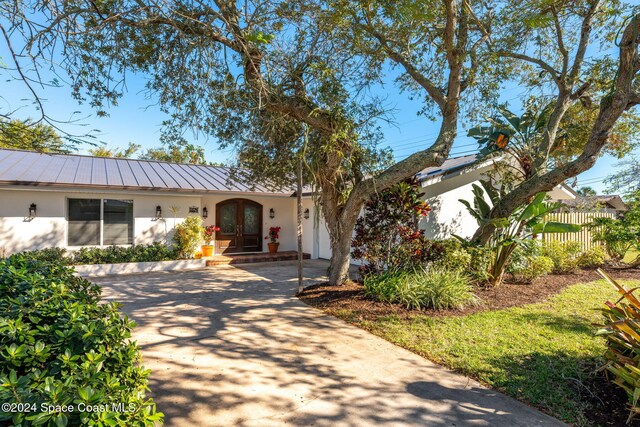 401 S Palm Ave, Indialantic, FL 32903 - view of front of property featuring french doors, stucco siding, concrete driveway, a metal roof, and a standing seam roof