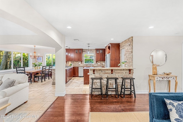 kitchen featuring decorative light fixtures, kitchen peninsula, backsplash, and appliances with stainless steel finishes