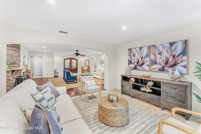 living room featuring a stone fireplace, ceiling fan, and light hardwood / wood-style flooring