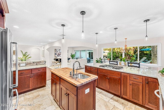 401 S Palm Ave, Indialantic, FL 32903 - kitchen with arched walkways, stainless steel appliances, a kitchen island with sink, recessed lighting, and stone tile flooring