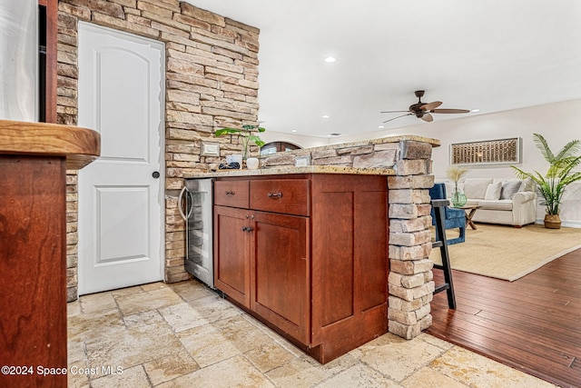 kitchen with ceiling fan, light hardwood / wood-style floors, light stone countertops, and wine cooler