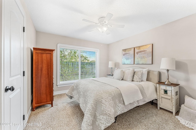 carpeted bedroom with ceiling fan and a textured ceiling