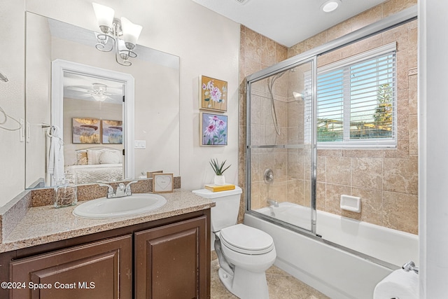 full bathroom with tile patterned floors, bath / shower combo with glass door, vanity, ceiling fan with notable chandelier, and toilet