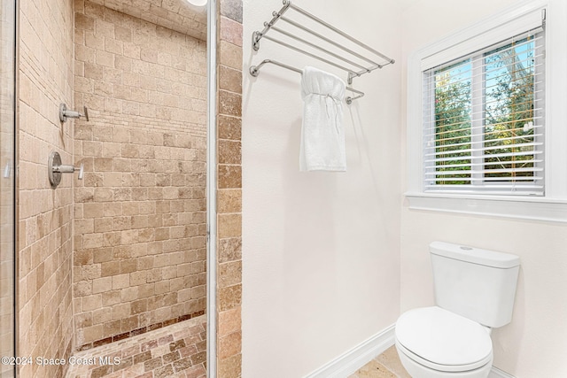 bathroom featuring a tile shower and toilet