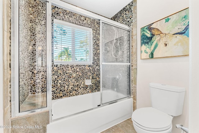 bathroom featuring combined bath / shower with glass door, tile patterned floors, and toilet