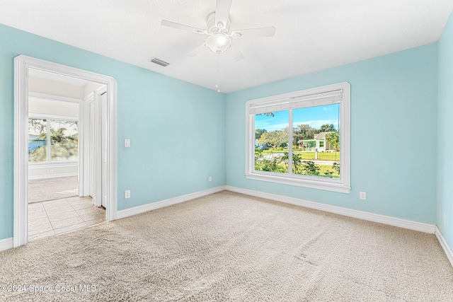 carpeted spare room with ceiling fan and a water view