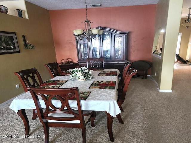 dining room with carpet flooring, a textured ceiling, and an inviting chandelier