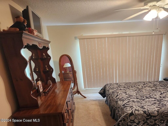 carpeted bedroom featuring ceiling fan and a textured ceiling