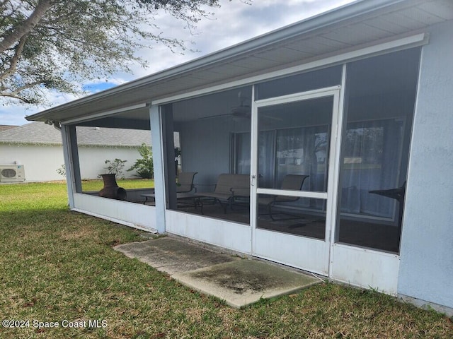 view of side of property featuring a sunroom, ac unit, and a yard