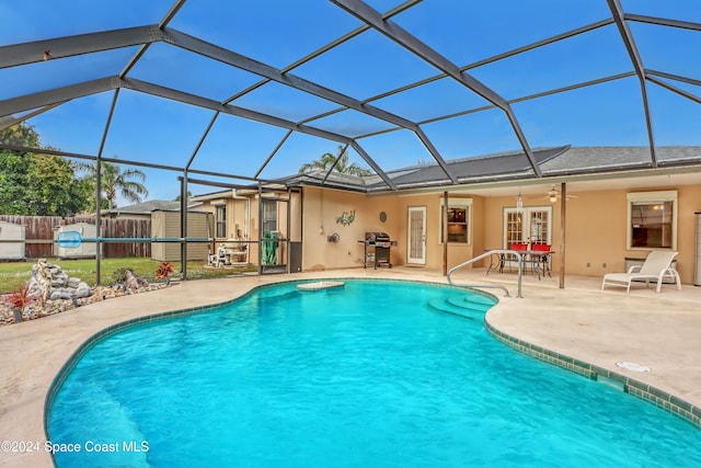 view of swimming pool featuring ceiling fan, area for grilling, a patio, and glass enclosure