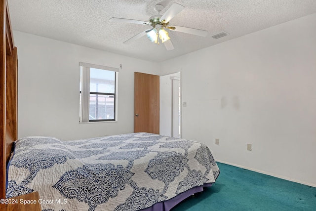 carpeted bedroom featuring ceiling fan and a textured ceiling