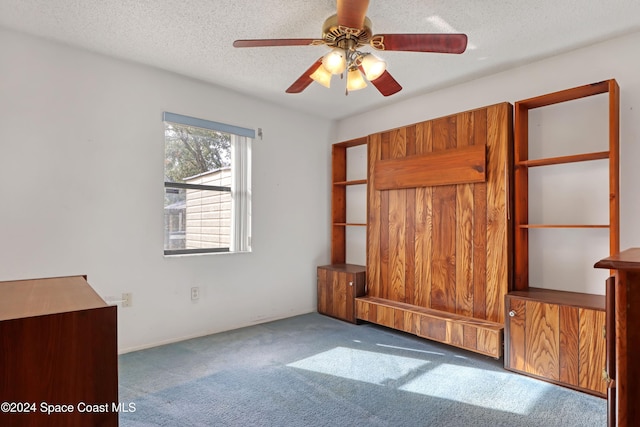 unfurnished bedroom with ceiling fan, dark carpet, and a textured ceiling