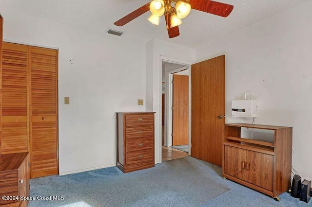 unfurnished bedroom featuring ceiling fan, light colored carpet, a textured ceiling, and a closet