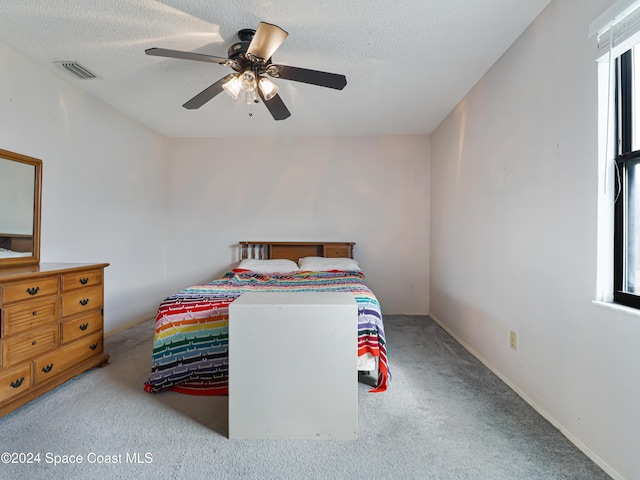 bedroom featuring light carpet, a textured ceiling, and ceiling fan