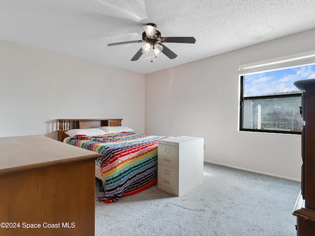 bedroom with ceiling fan, light carpet, and a textured ceiling