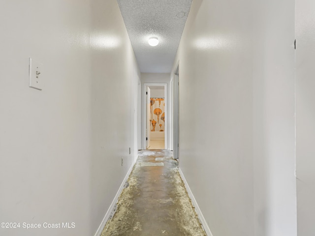 hallway with concrete flooring and a textured ceiling