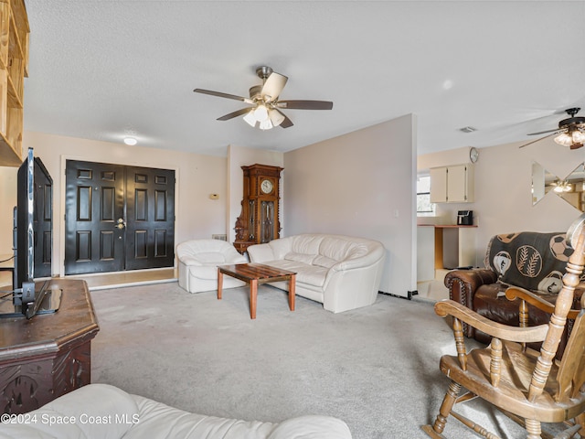 living room featuring light carpet, ceiling fan, and a textured ceiling