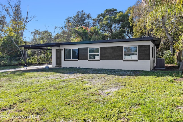 view of side of property featuring central AC unit, a carport, and a lawn