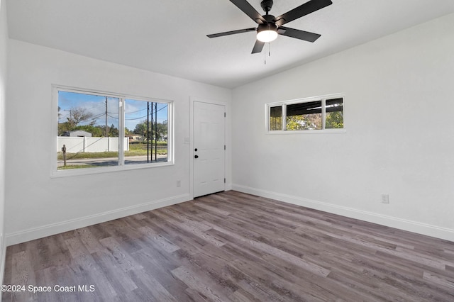 empty room with wood-type flooring, vaulted ceiling, and a healthy amount of sunlight