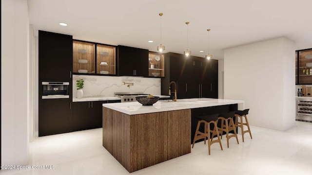 kitchen featuring pendant lighting, oven, decorative backsplash, an island with sink, and dark brown cabinetry