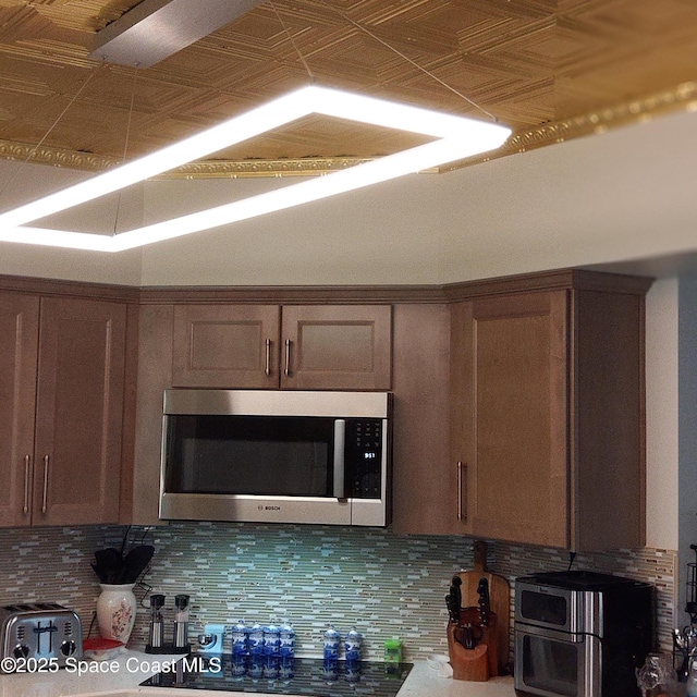 272 Aquarina Blvd Unit 272, Melbourne Beach, FL 32951 - kitchen featuring stainless steel microwave, backsplash, and an ornate ceiling