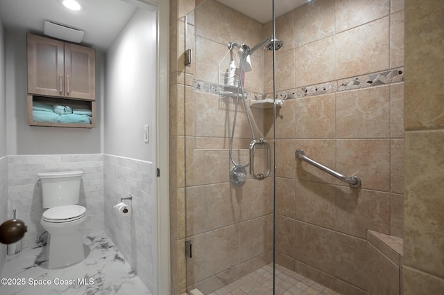 bathroom with tile walls, a shower with door, and toilet