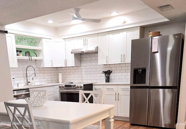 kitchen with appliances with stainless steel finishes, decorative backsplash, white cabinetry, and sink