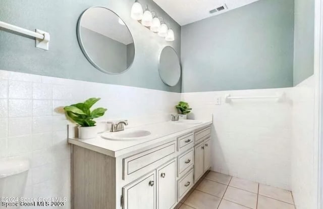 bathroom with toilet, tile patterned flooring, tile walls, and vanity