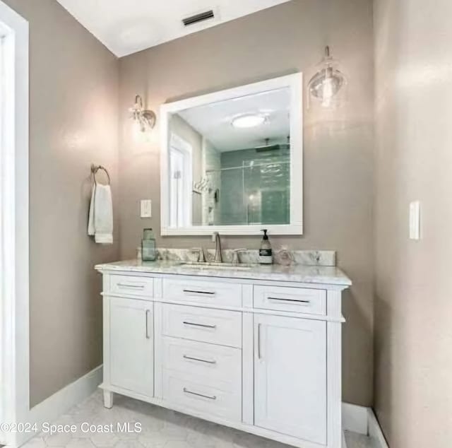 bathroom featuring a shower with shower door and vanity