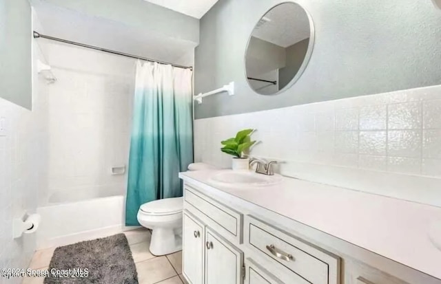 bathroom with tile walls, shower / bathtub combination with curtain, toilet, vanity, and tile patterned floors