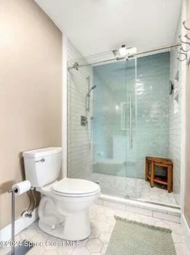 bathroom with toilet, tile patterned flooring, and a shower with door