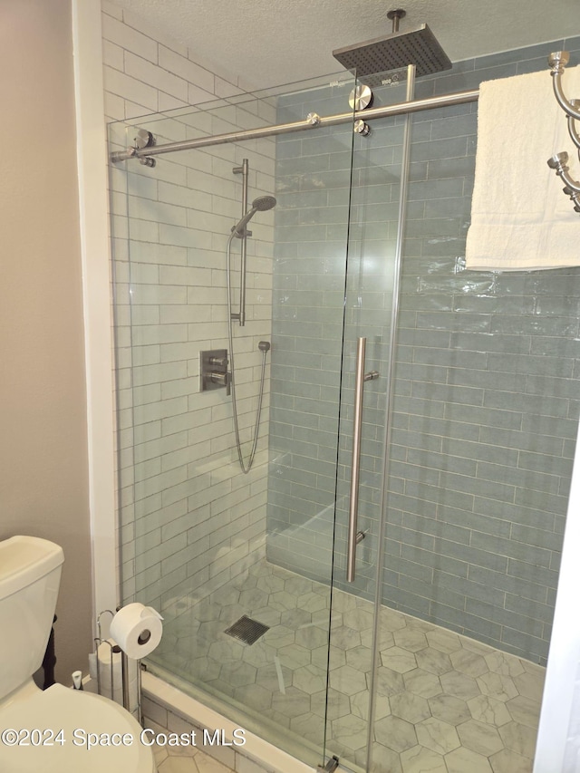 bathroom featuring a textured ceiling, an enclosed shower, and toilet