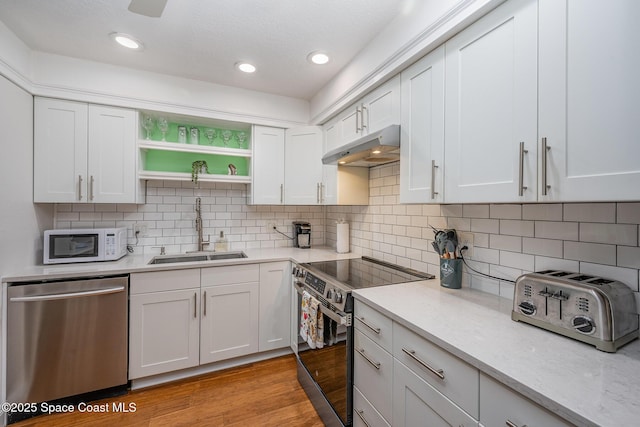 kitchen featuring stainless steel appliances, white cabinets, a sink, and under cabinet range hood