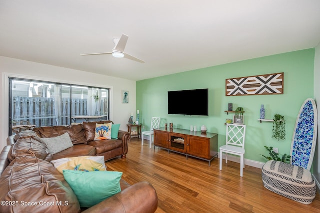 living area featuring ceiling fan, baseboards, and wood finished floors