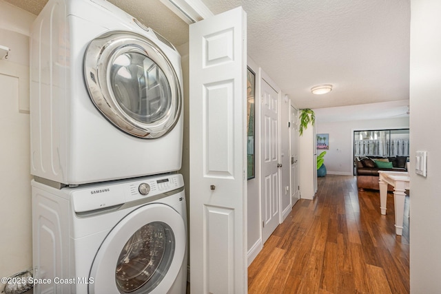 laundry area with a textured ceiling, laundry area, baseboards, dark wood finished floors, and stacked washer and clothes dryer