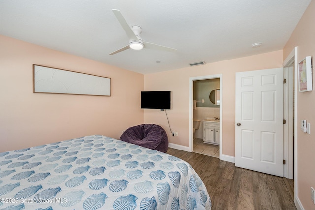 bedroom with baseboards, visible vents, connected bathroom, ceiling fan, and wood finished floors