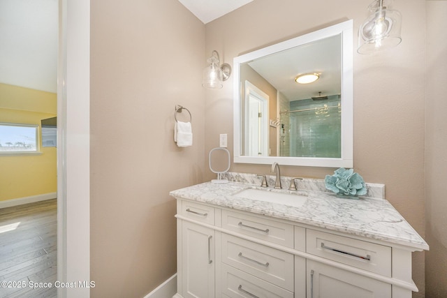 full bathroom featuring wood finished floors, a shower stall, vanity, and baseboards