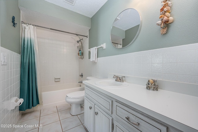 bathroom with a textured ceiling, tile patterned flooring, vanity, tile walls, and shower / bath combo with shower curtain