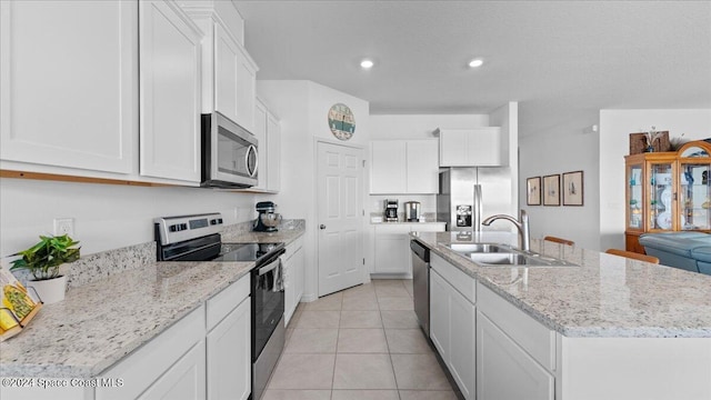 kitchen with white cabinetry, appliances with stainless steel finishes, sink, and a center island with sink