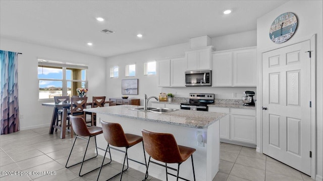 kitchen featuring sink, white cabinetry, a kitchen breakfast bar, stainless steel appliances, and an island with sink